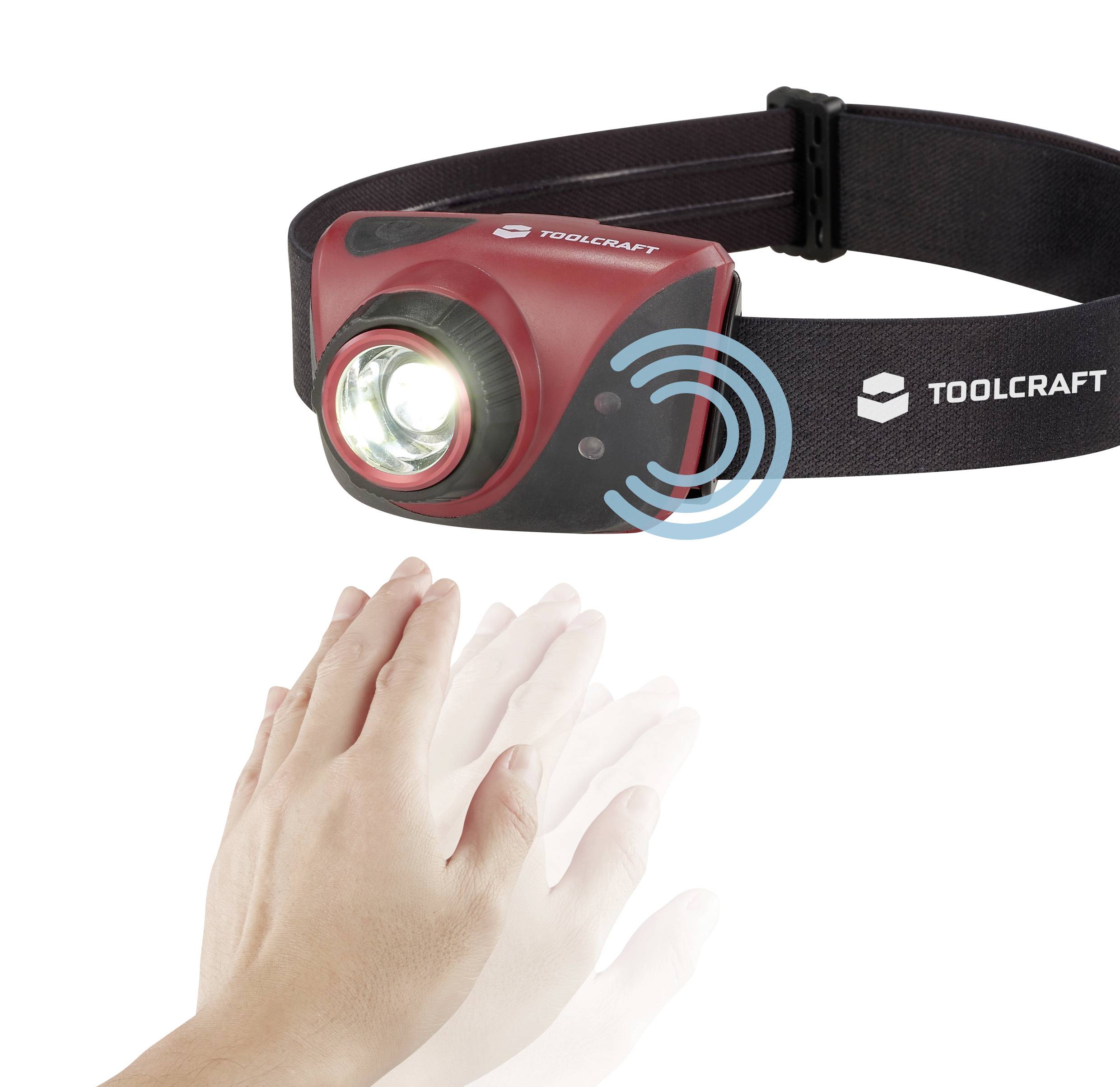 A hand activates a red head torch using gesture control. The lamp shines brightly and is mounted on a black headband.