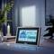 A digital weather station screen displaying indoor and outdoor temperature readings in a modernly furnished room.