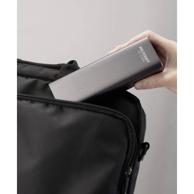A hand is placing a black portable power bank into a bag.