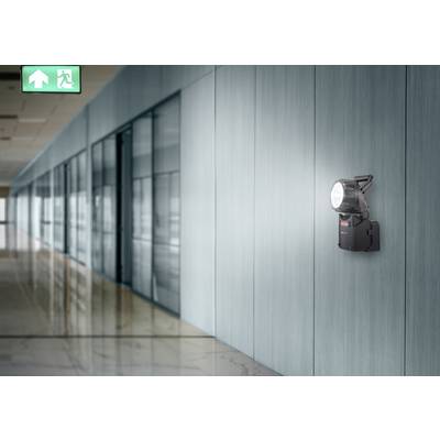 'Corridor with a green emergency exit sign on the ceiling and a wall-mounted light fitting illuminating the way.'