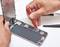 A person is repairing an opened smartphone, using a red tool to work on internal components.