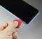 A person is using a red plastic tool to open a mobile phone. The smartphone is blue and is being worked on from the side.