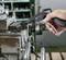 A person is holding a tool in their hand. In the background, an industrial workshop machine can be seen.