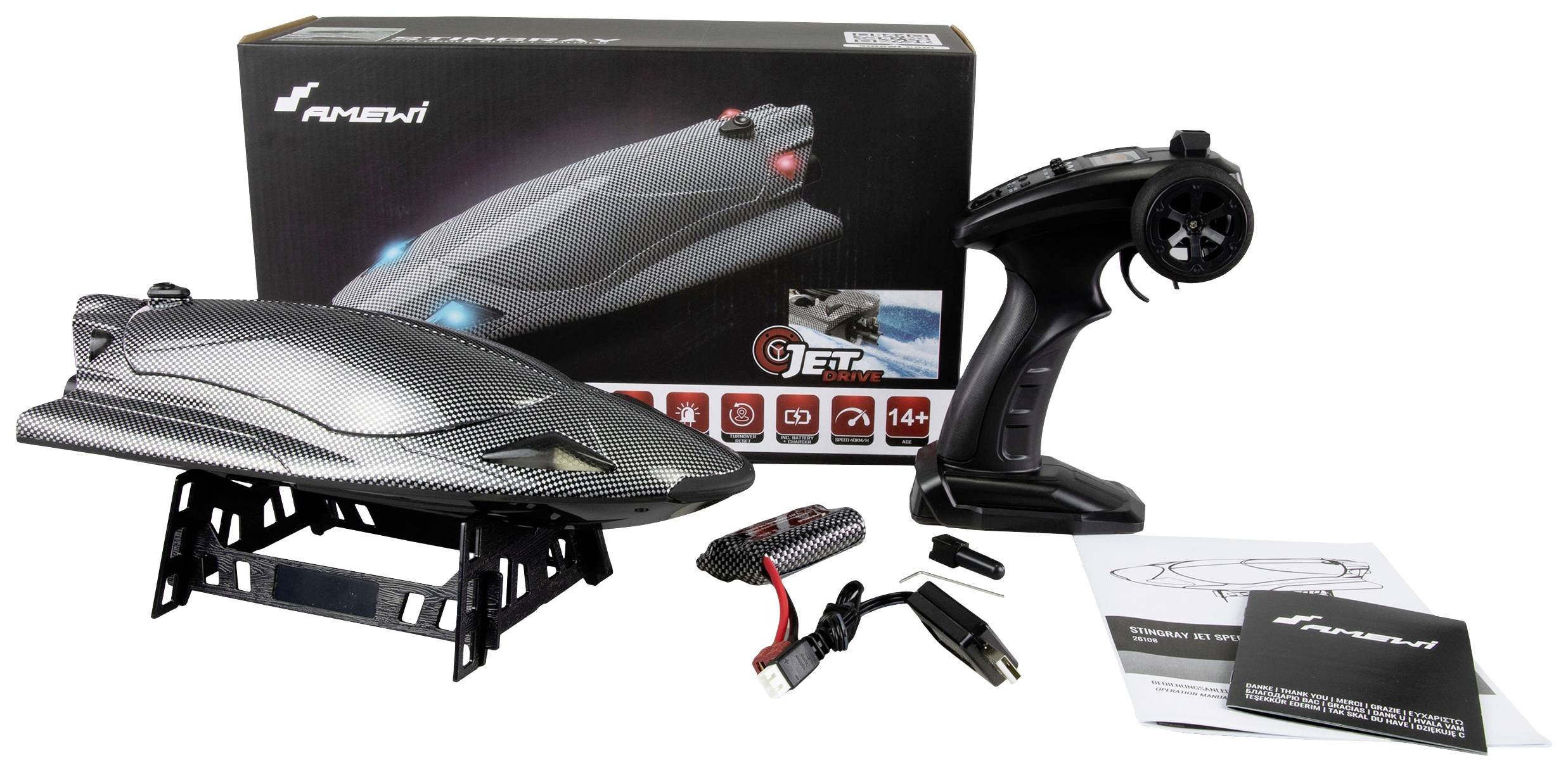A remote-controlled mini submarine set on a table with controls, charger, cables, and instructions in front of its packaging.