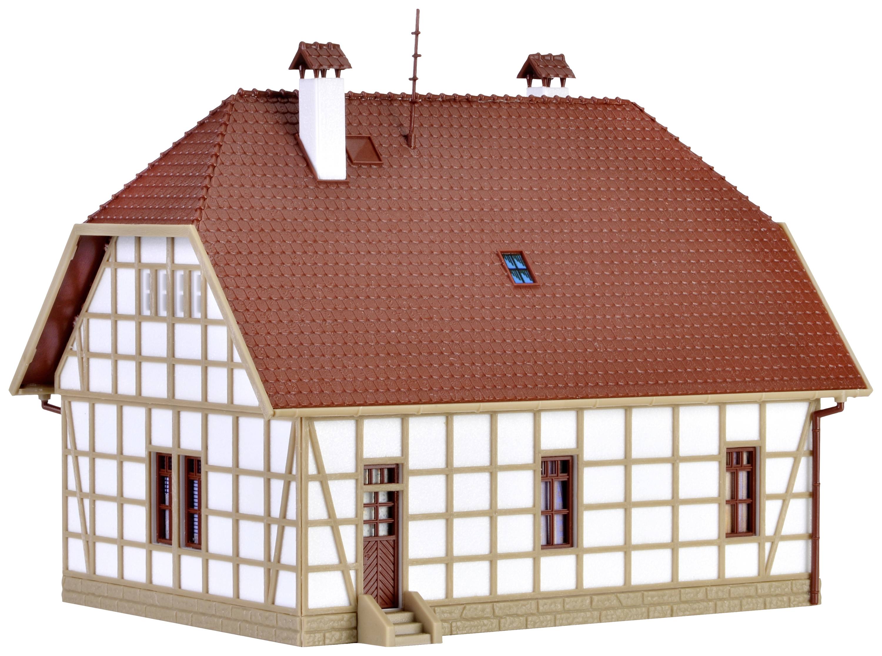 A model house in half-timbered style with a white façade and brown roof. It has multiple windows, an entrance door and is designed with intricate details.
