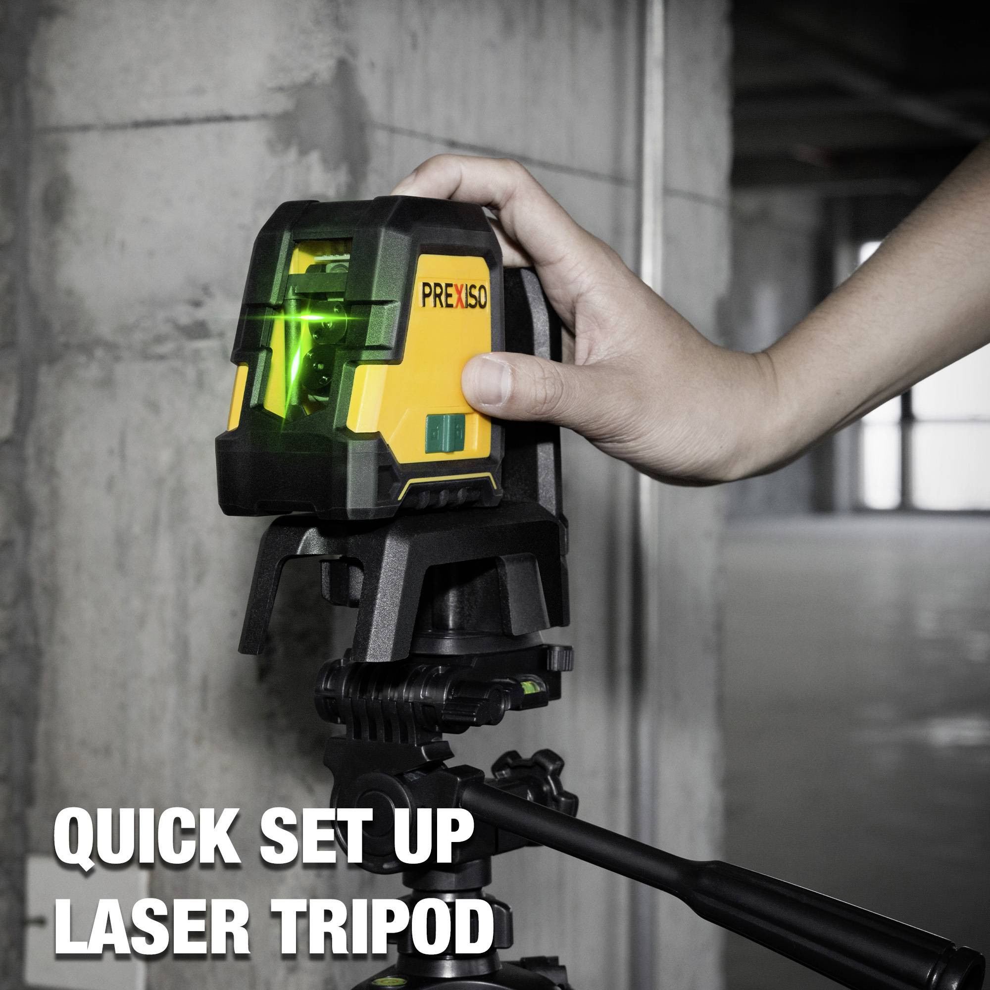 A person is aligning a laser on a tripod in a room. The laser projects green lines used for alignment.
