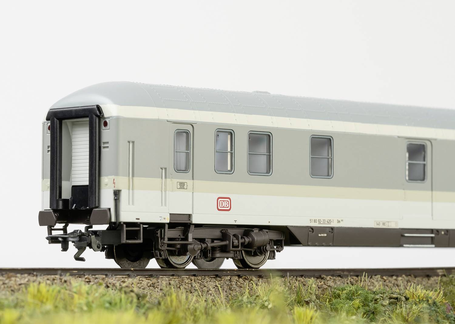 A model of a grey-white German sleeping car from Deutsche Bahn, with DB logo, on a section of track with grass in the foreground.