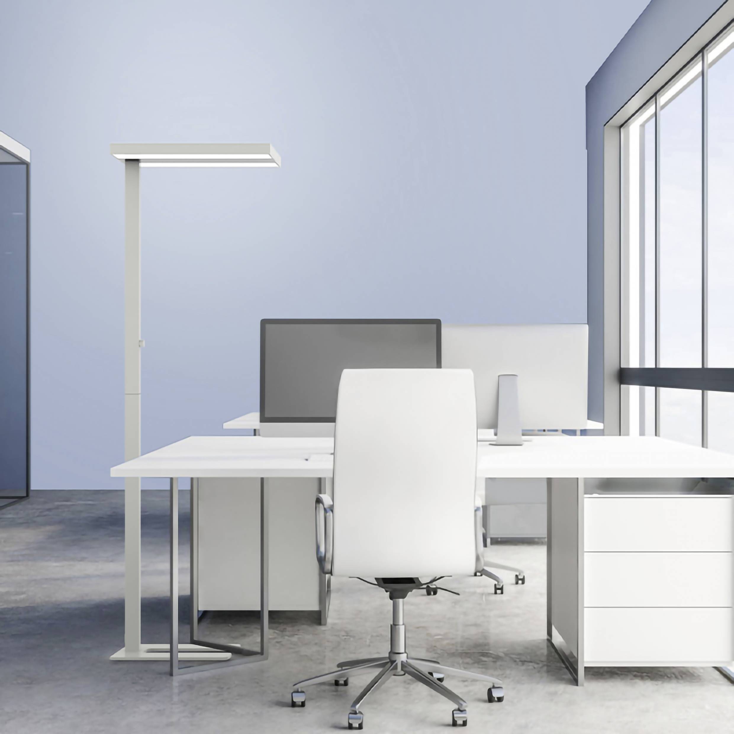 Modern office setup with a desk, white swivel chair, two monitors and a standing lamp in front of large windows.
