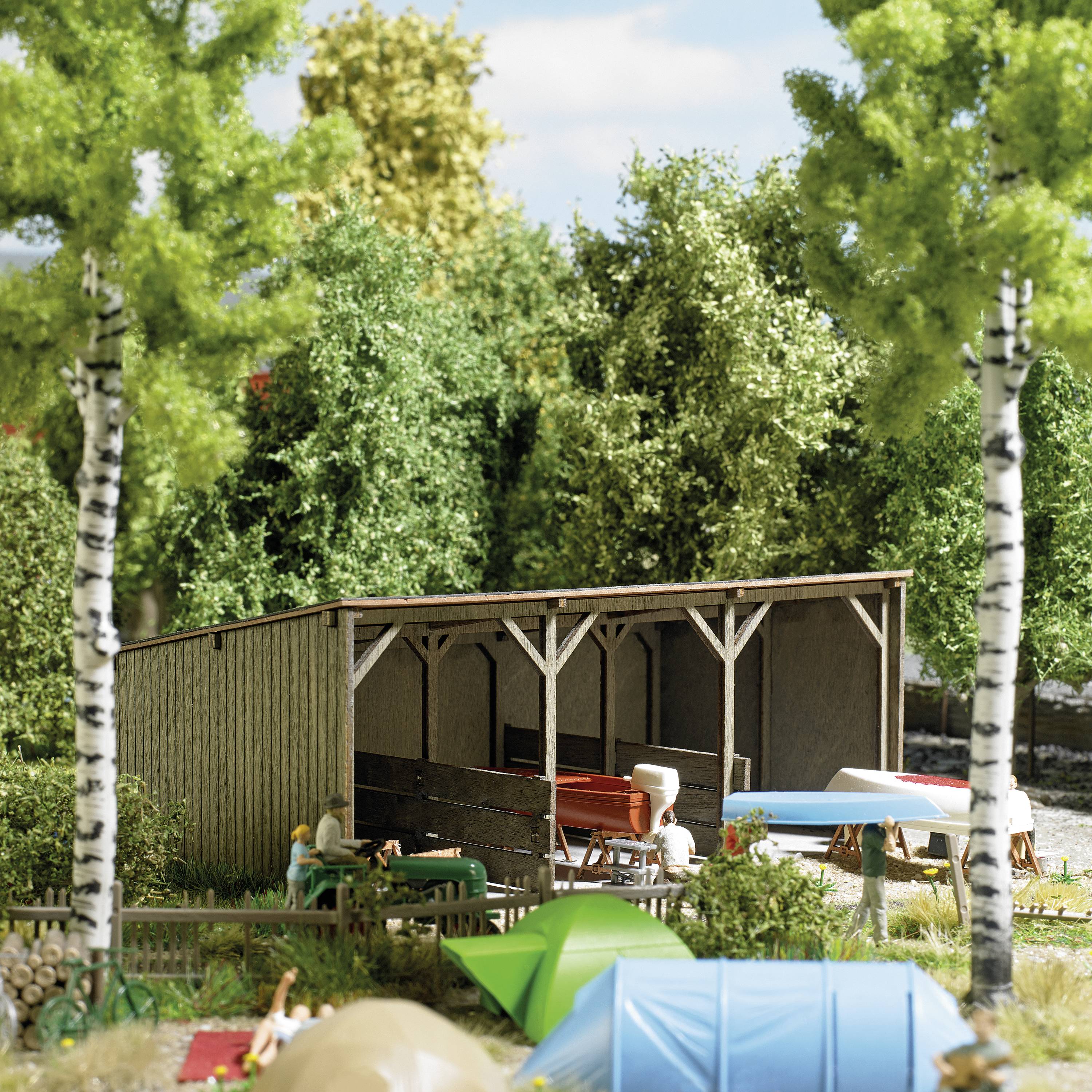 A miniature model of a campsite with tents, trees, and a wooden cabin. People enjoying nature.