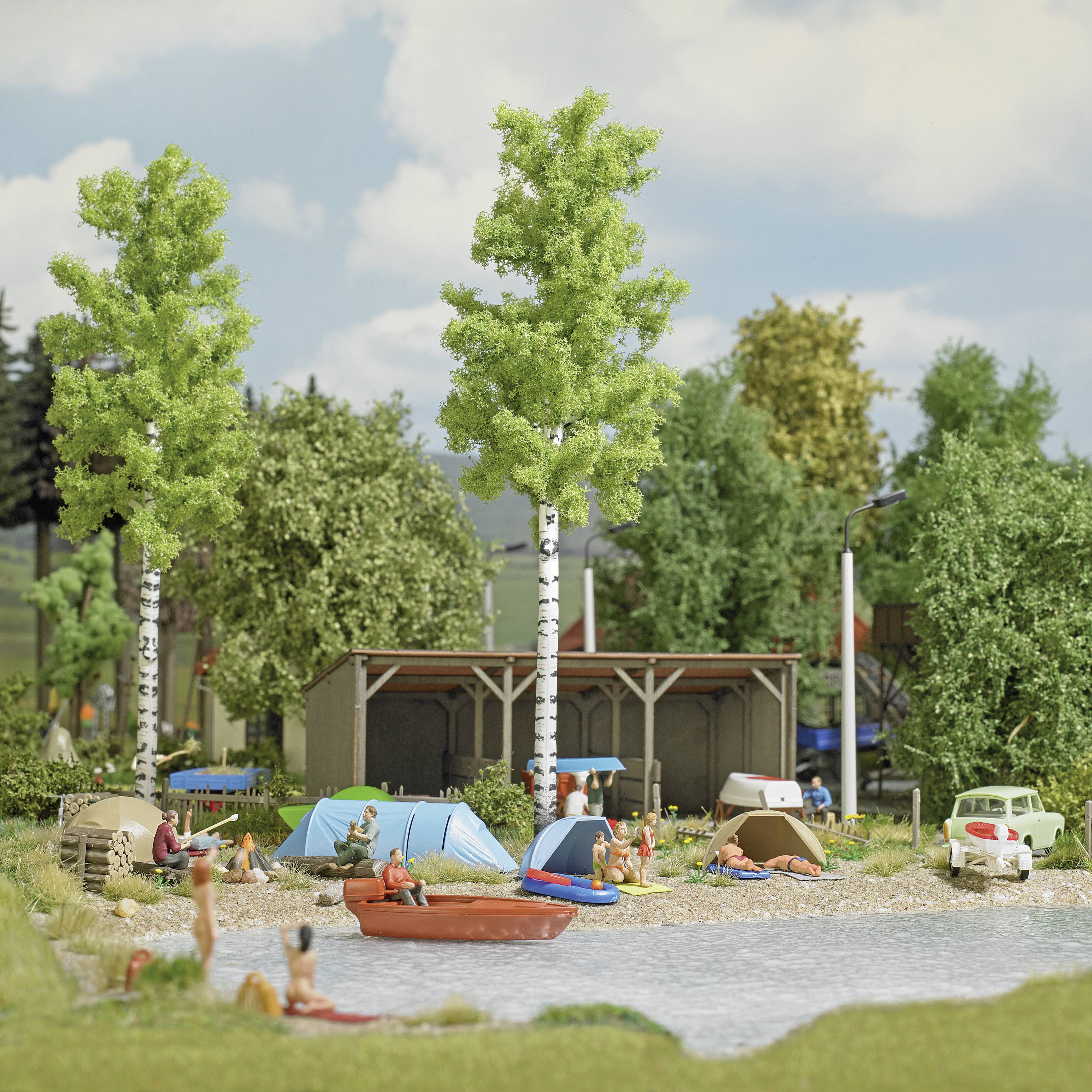 Campsite with tents and caravans by the lake. People swimming and relaxing on the shoreline. Surrounded by trees and nature.