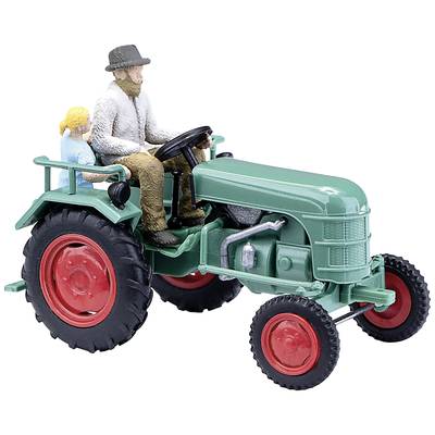 A model tractor with a man at the wheel and a child as a passenger. Both figures are sitting on the green tractor with red wheels.