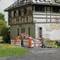 Workers in orange clothing are repairing a road in front of an old building. Road signs indicate ongoing roadworks.