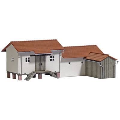 A small model building with red tiled roofs and a detailed staircase. The building is slightly elevated on wooden posts above the ground.