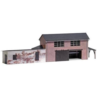 A brick building in model scale with a crumbling façade and large wooden door, reminiscent of a warehouse or workshop.