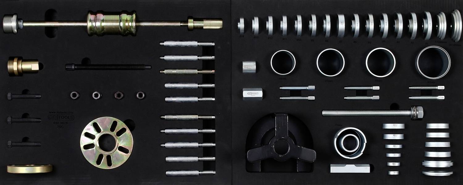 Tool set in a black foam insert with various metal parts, screwdrivers, springs, and clips.