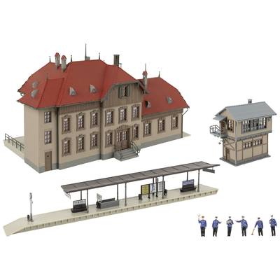 A model railway station with a red roof, platform, signal system, and a set of figures in uniform.