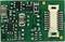 A small green circuit board with various surface-mounted (SMD) components, including resistors and capacitors, on its surface.