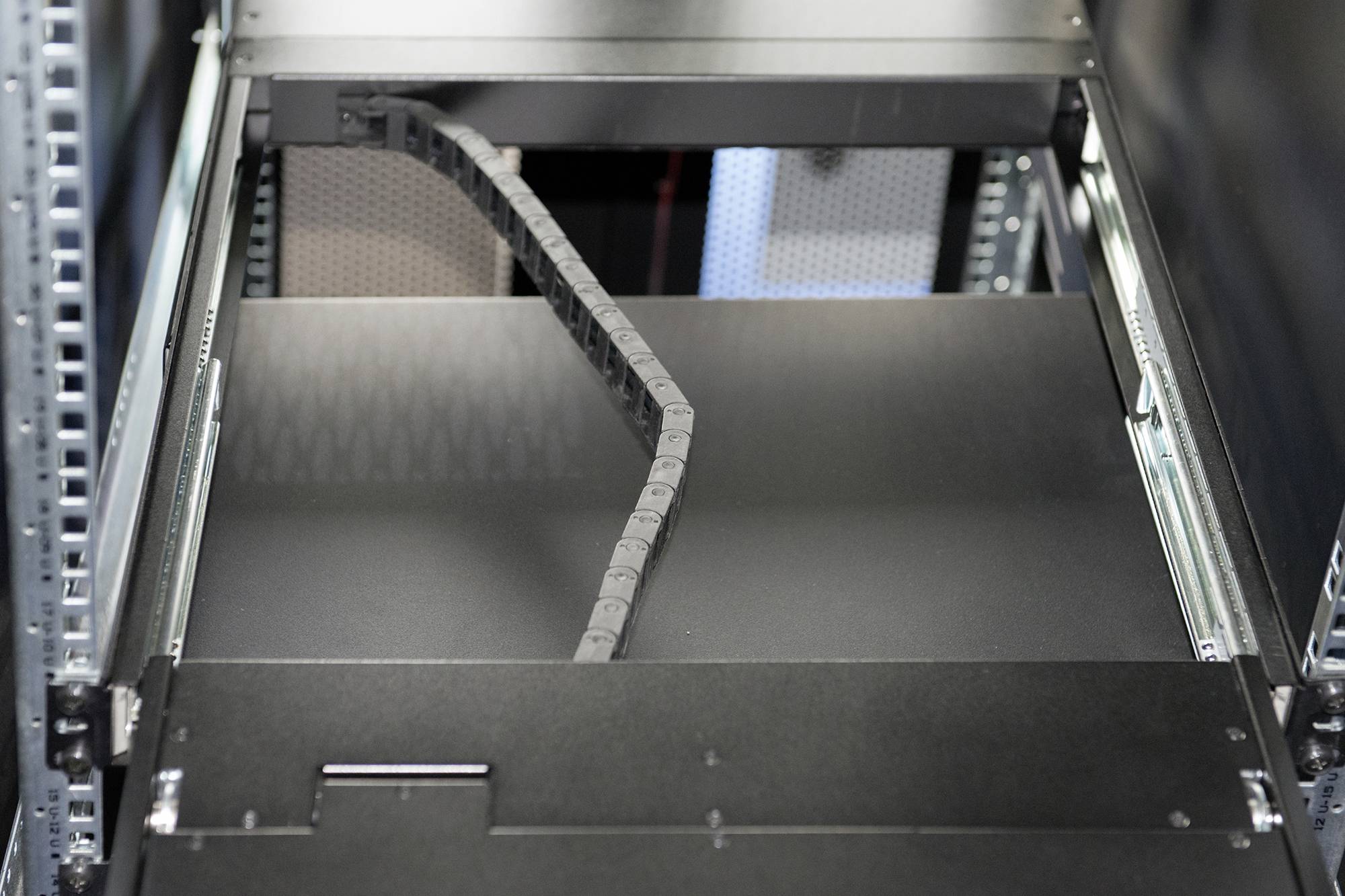 An empty server bay in a server rack, with a flexible cable management system. The scene conveys technical infrastructure.
