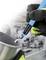 A gloved hand is holding a blue soldering iron tool working on a piece of metal. A workshop is blurred in the background.
