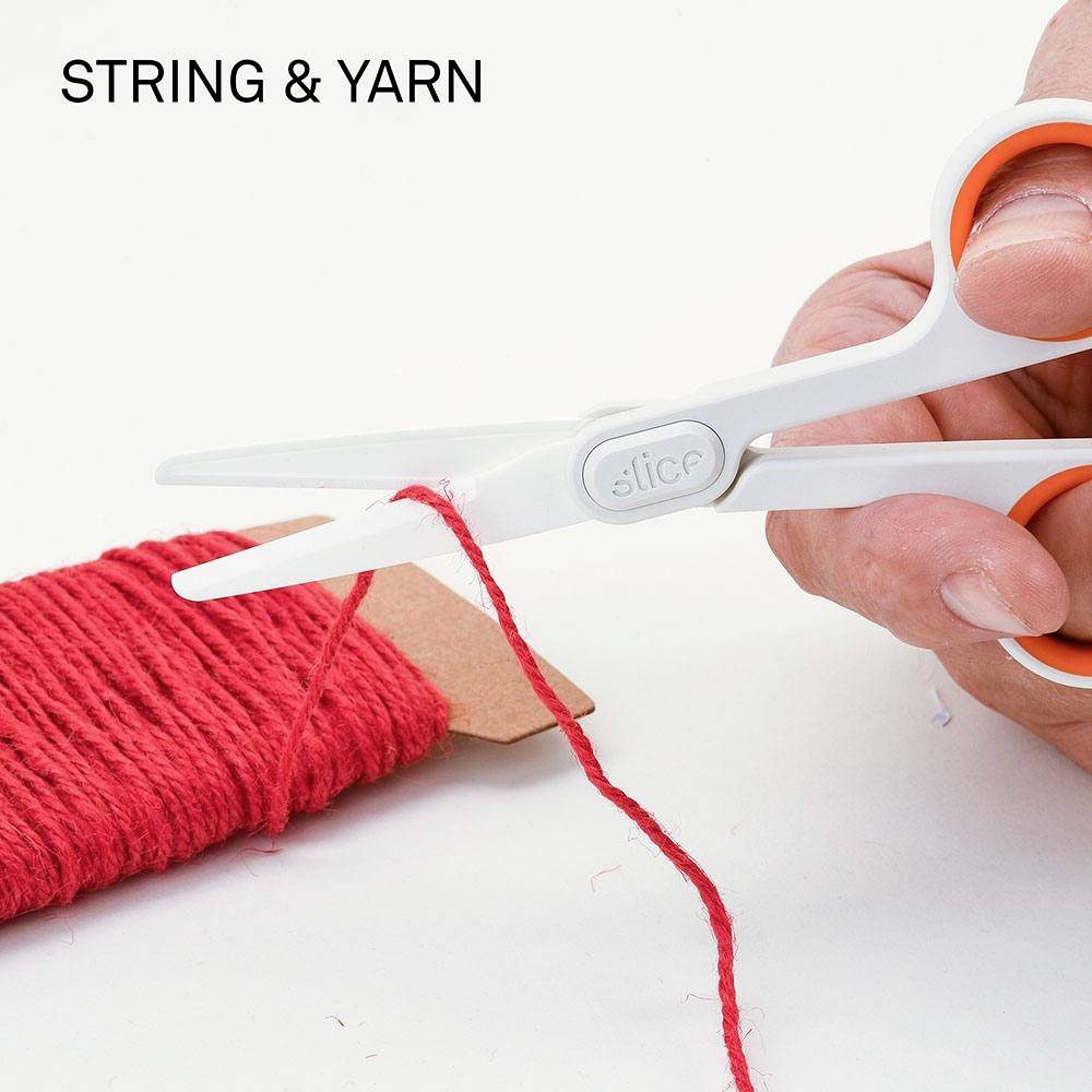 A hand cuts red thread from a cotton reel with a white pair of scissors. Text: 'STRING & YARN'.