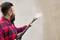 A man with a beard is cleaning a wall with a pressure washer. The right side of the wall is clean, while the left side remains dirty.