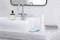 A modern washbasin in the bathroom with a tap, toothpaste, toothbrush and towel; neutral background.