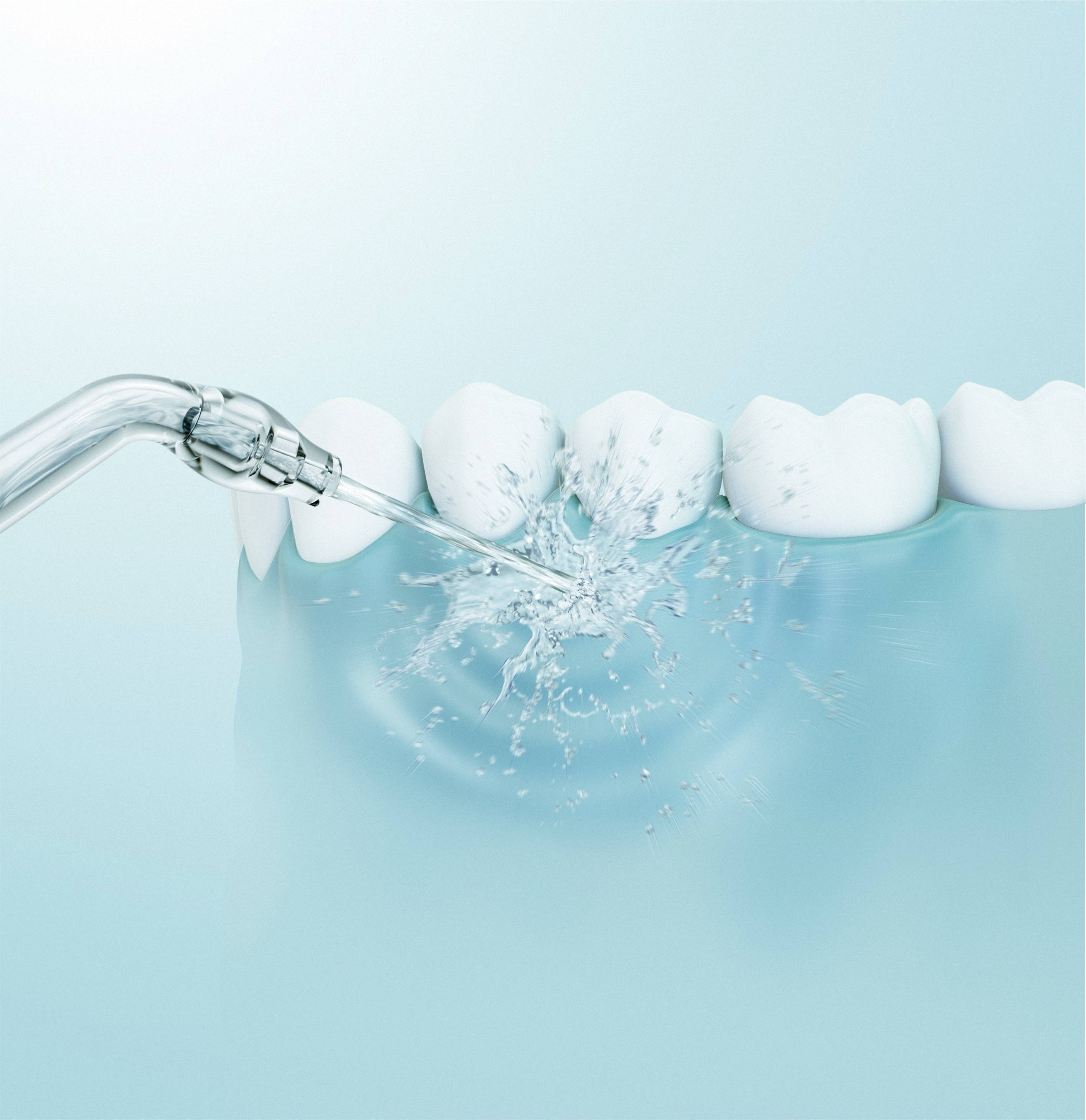 A water jet cleans white teeth in a row on a blue background, demonstrating dental hygiene and care.