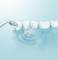 A water jet cleans white teeth in a row on a blue background, demonstrating dental hygiene and care.