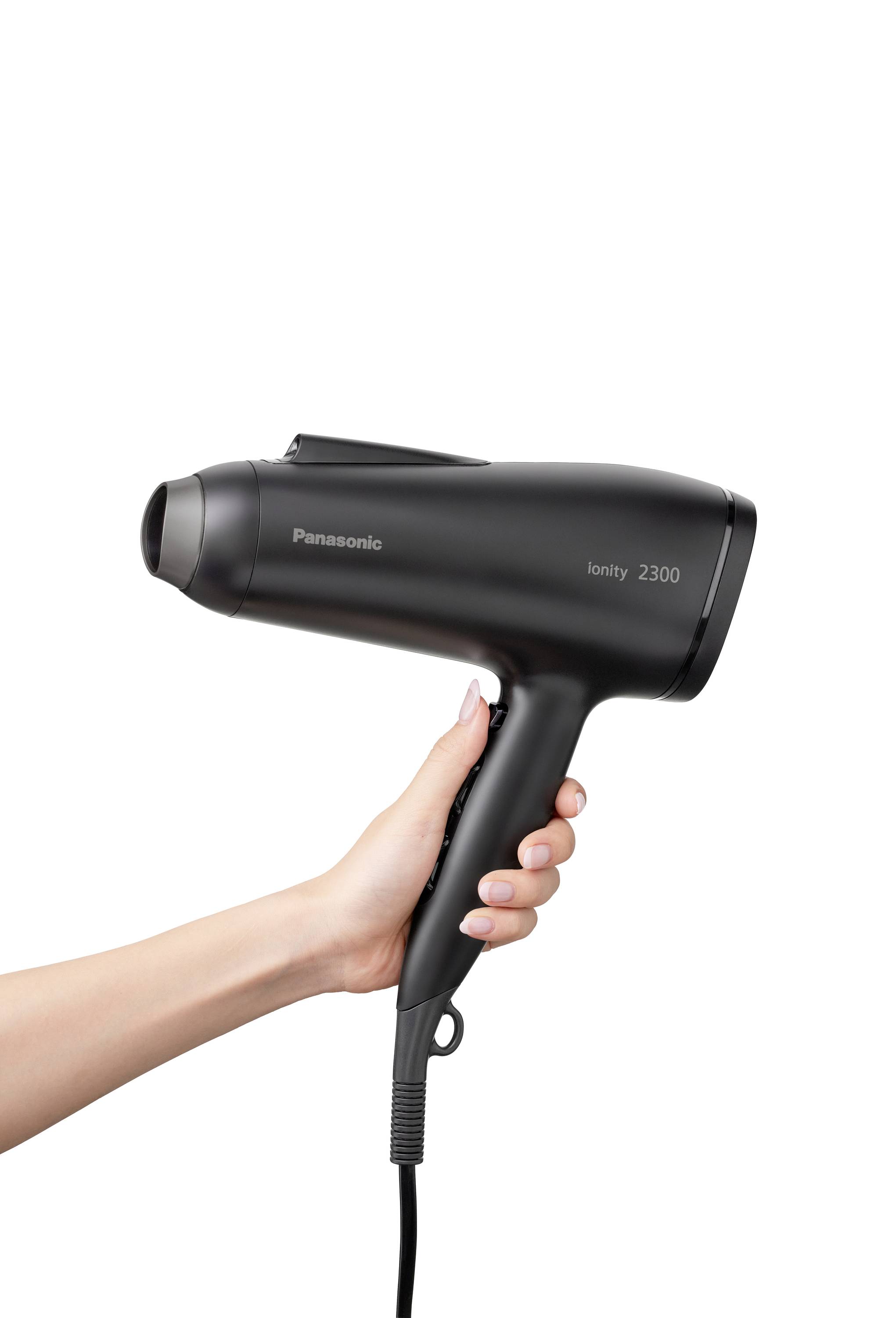 A hand is holding a black Panasonic hairdryer, model Ionity 2300. The hairdryer has a sleek design and an electrical cord.