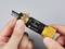 A hand is holding a yellow, adjustable torque wrench from TOOLCRAFT. The tool displays a scale with various markings.