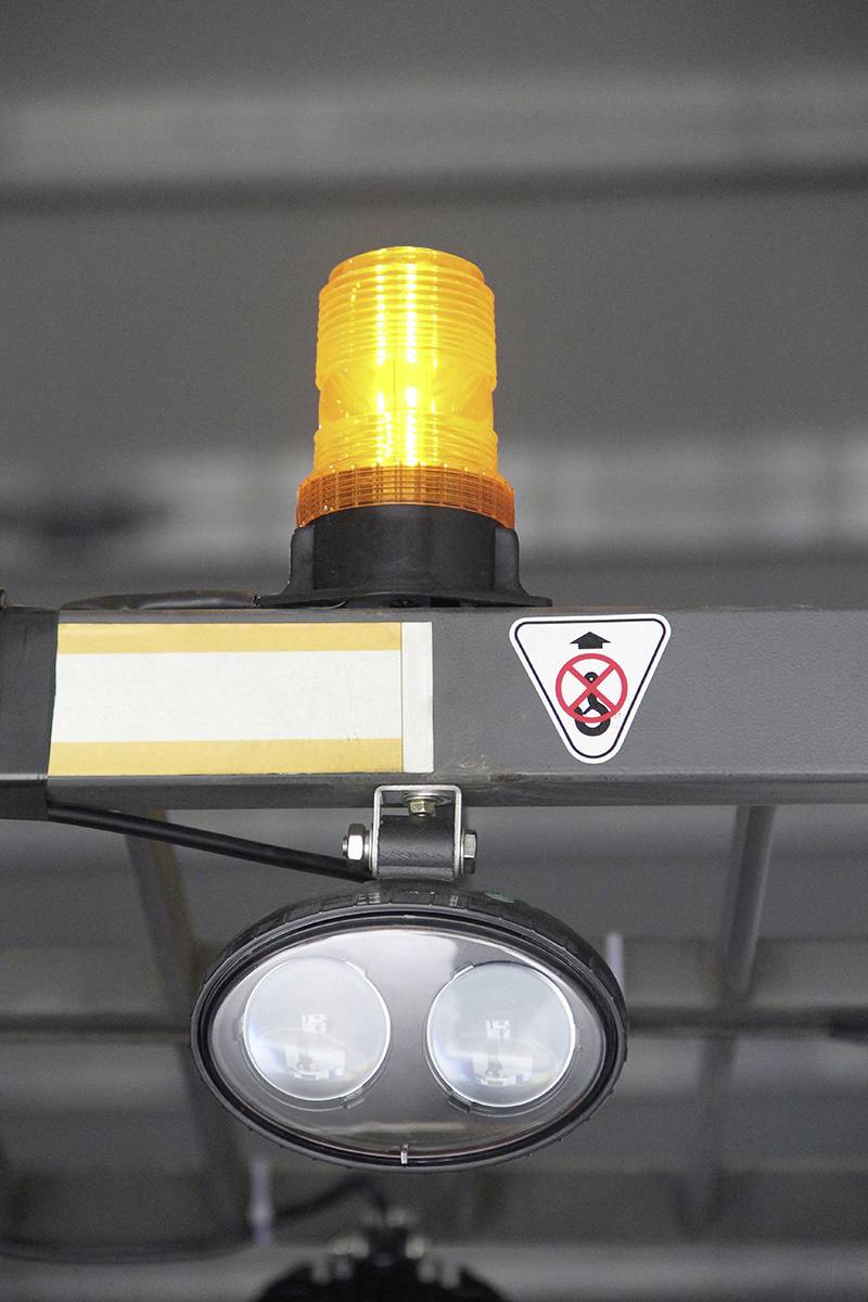 An orange warning light is illuminated, beneath which is a sign with a crossed-out symbol of a man wearing a hat.