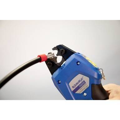 A person is using a blue crimping tool to secure a metal connector on a black cable.