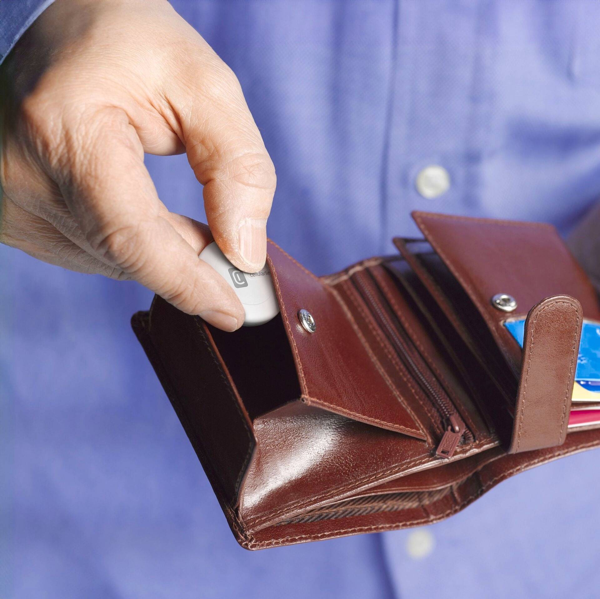 A hand holds an amber-coloured wallet open. A USB stick is being removed. Credit cards are visible alongside it.