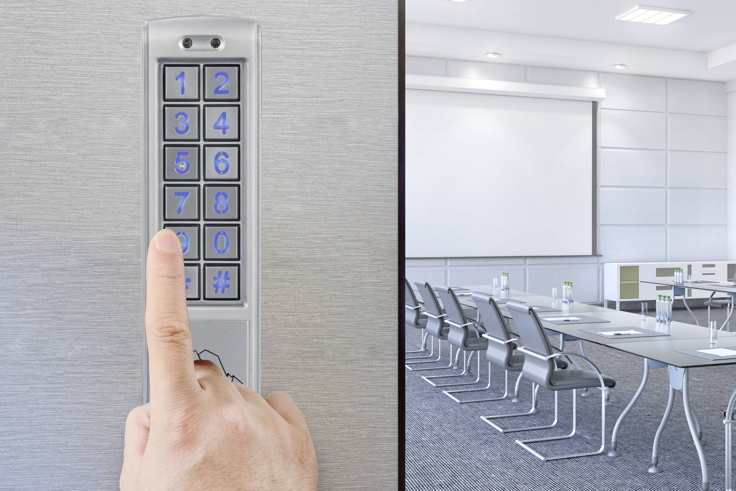 A hand presses a key on a number pad mounted beside an empty conference room.