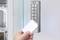 A hand is holding a white access card in front of an electronic door lock with a keypad and numerical keys from 0 to 9.