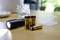 A black torch illuminates on a wooden table next to three AA batteries and a transparent battery casing.