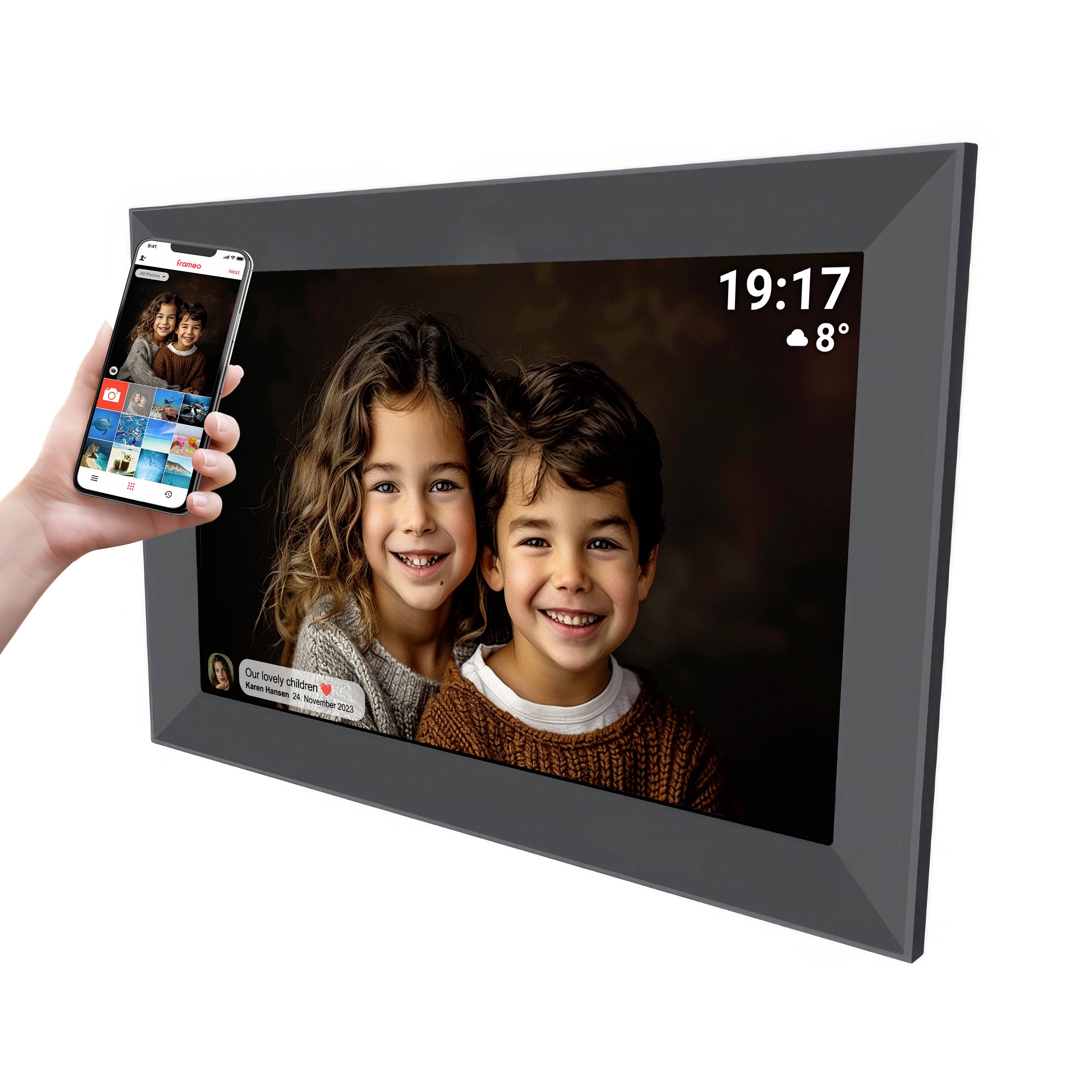 A digital photo frame displays an image of two smiling children. A hand holds a mobile phone with the same picture displayed. Time and temperature shown in the top right corner.