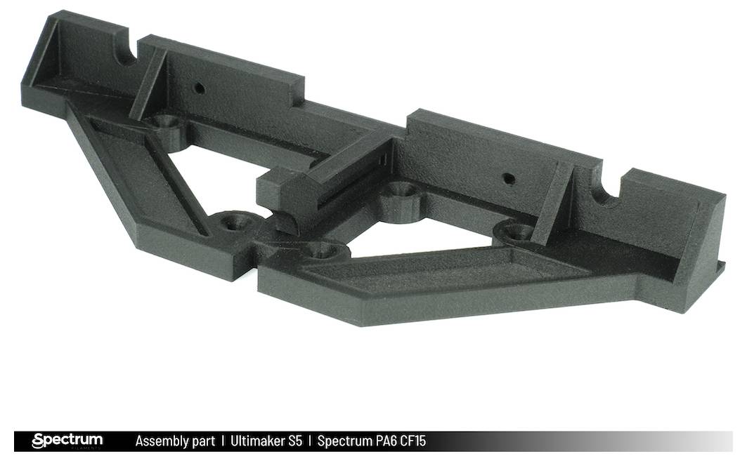 Black plastic component with complex geometry, used for assembly in the Ultimaker S5 3D printer, manufactured from Spectrum PA6 CF15 material.