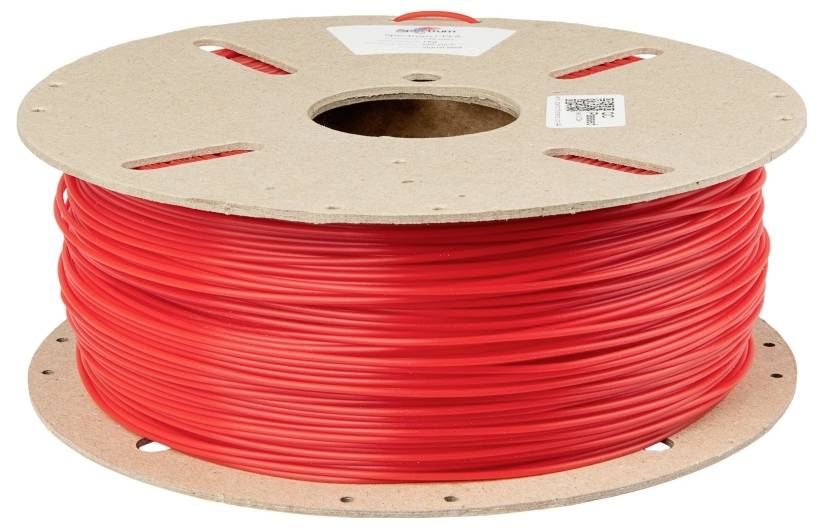 A large cardboard spool core with wound red plastic filament, used for 3D printers.