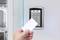 A hand holds a card up to an electronic access control system with a numeric keypad on a glass door.
