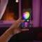 A hand is holding a smartphone with an app that allows control of a lightbulb in various colours.