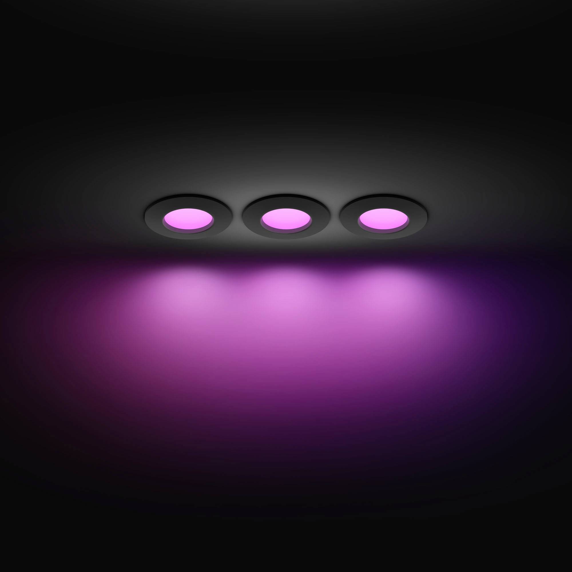 Three purple illuminated ceiling spotlights in a dark room; uniform downward lighting.