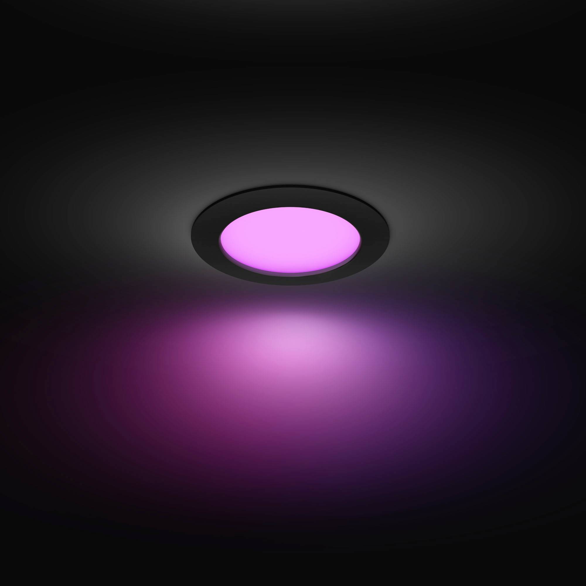 A round ceiling spotlight glows in vibrant magenta, casting a colourful light across the dark surroundings.