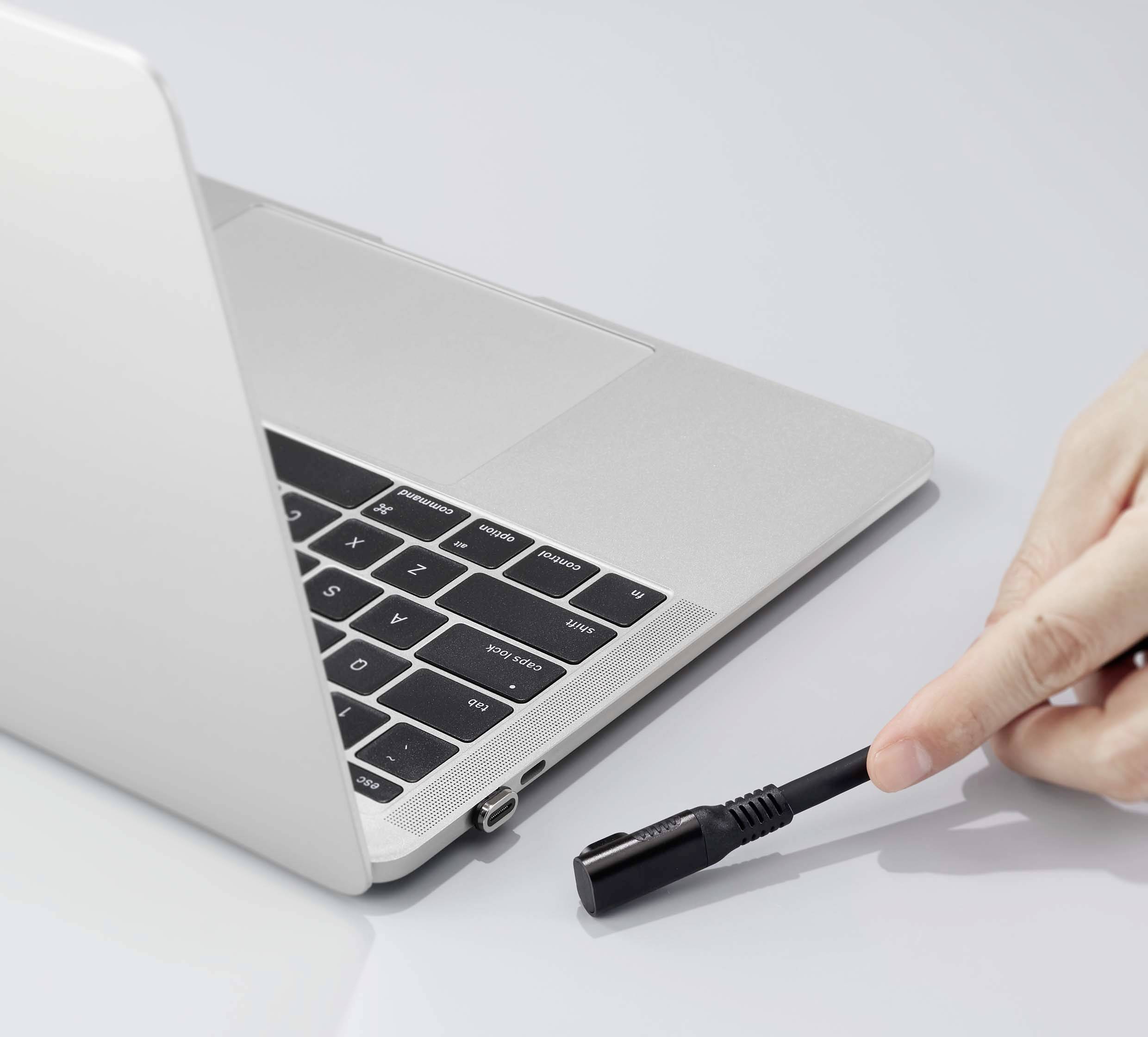 A person plugs a charging cable into a laptop.