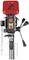 A red pillar drill with digital display and control buttons, three hand levers, and a safety housing at the bottom.