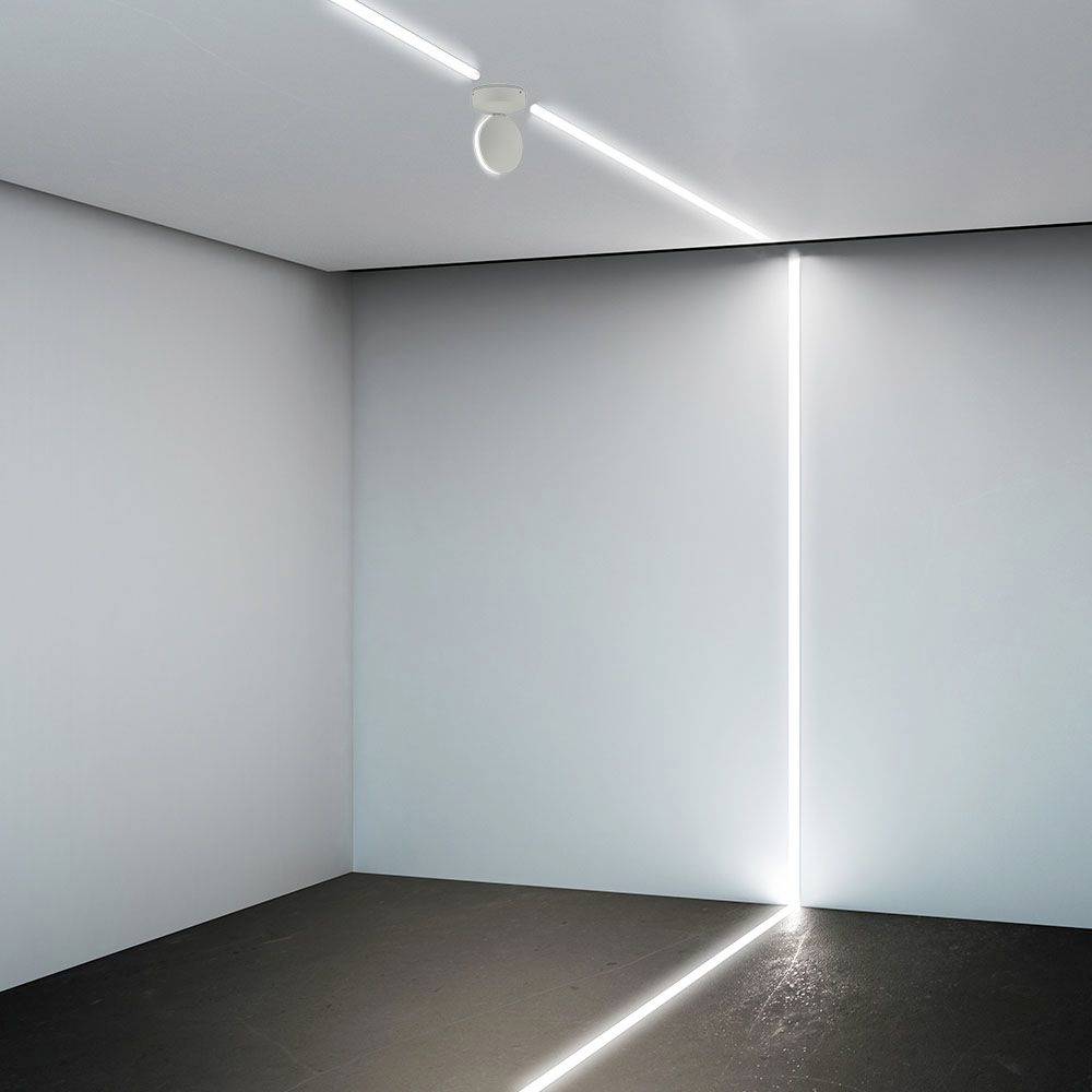 A minimally lit room with thin, luminous lines on the wall and ceiling that intersect at right angles.
