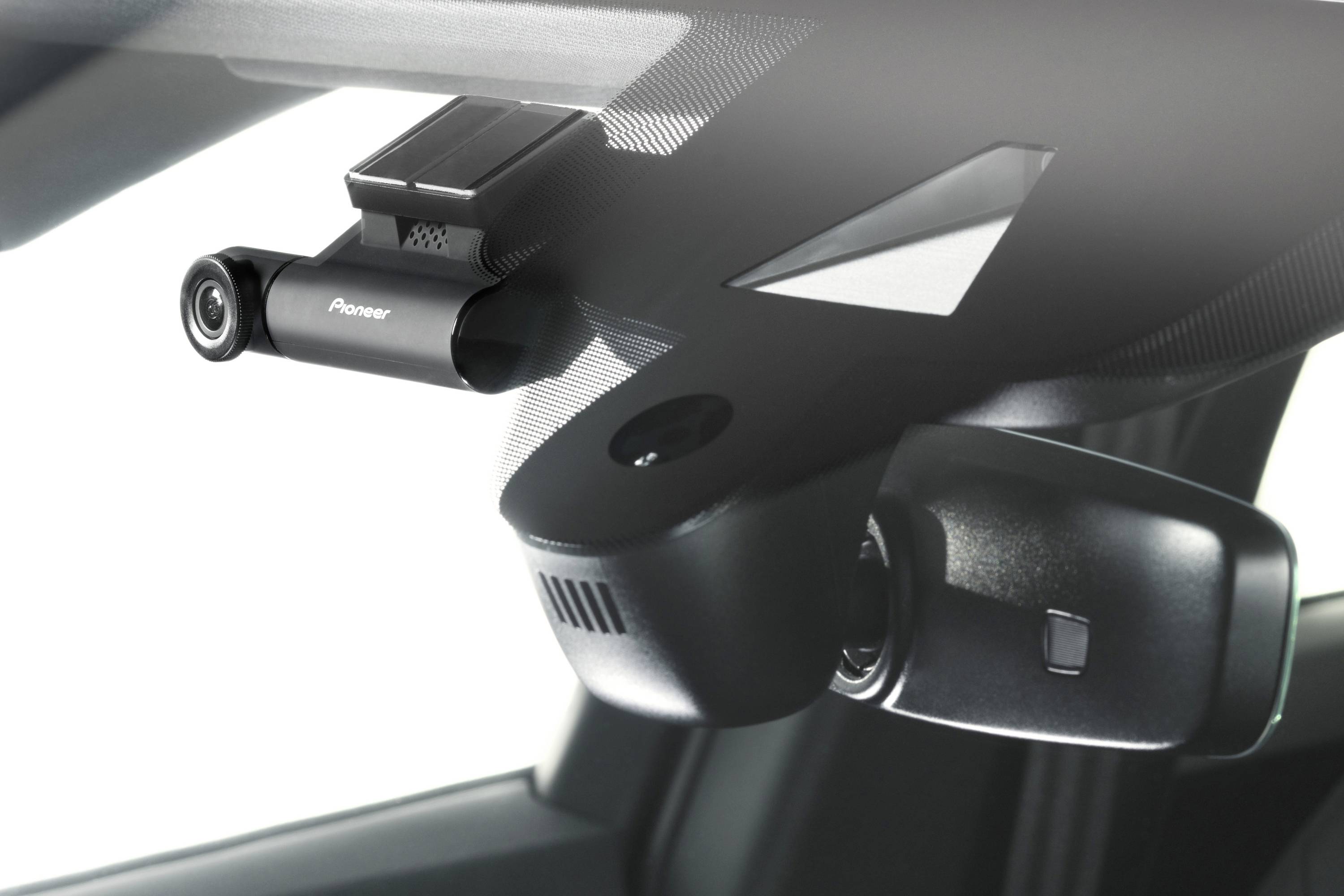 A dashboard camera is mounted on the windscreen of a vehicle. It faces forward and is used to record the journey.