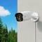 Security camera mounted on a wall, looking out over a forest under a clear sky.