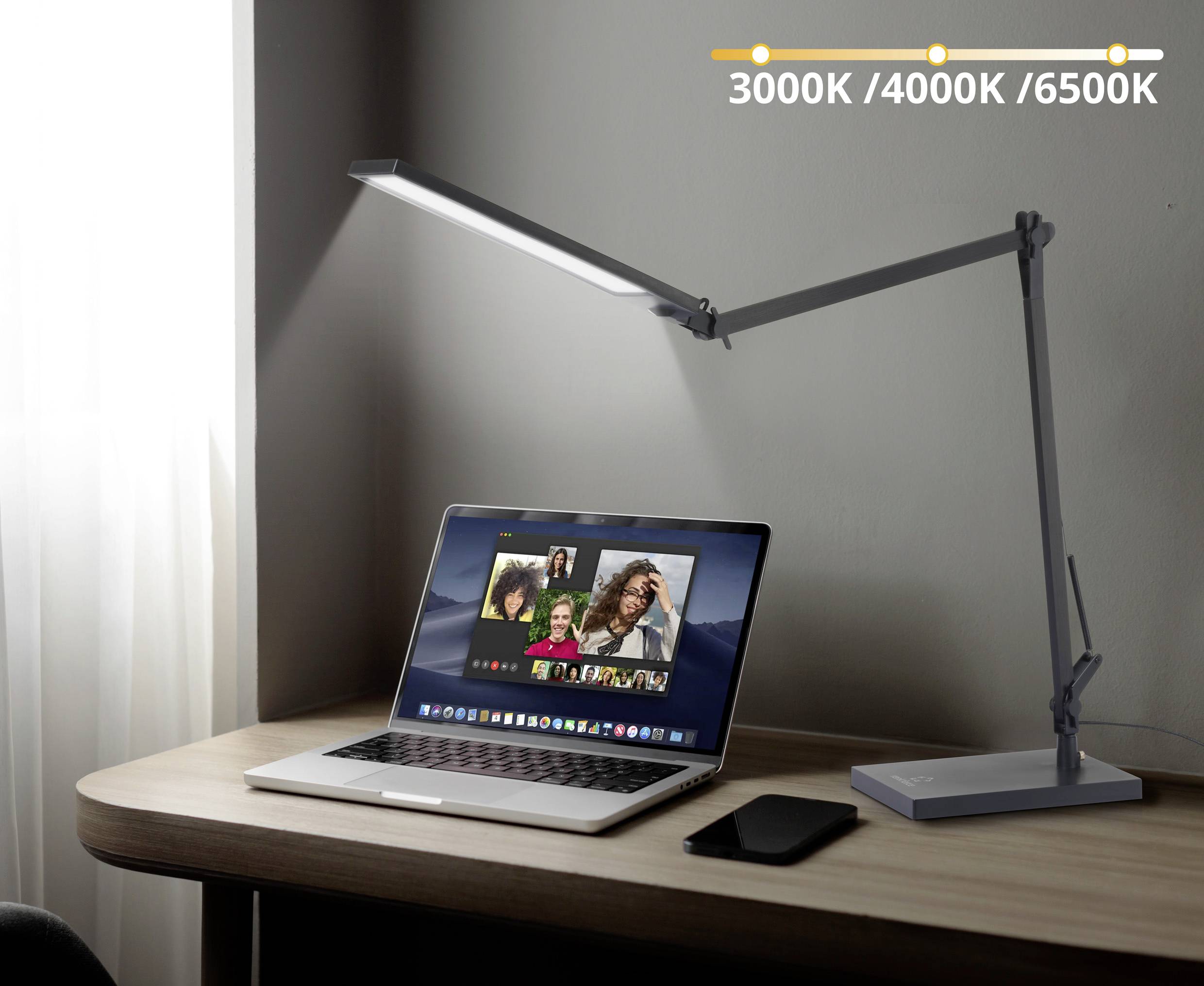 A laptop with an active video call on a wooden desk under an adjustable desk lamp offering colour temperatures from 3000K to 6500K.