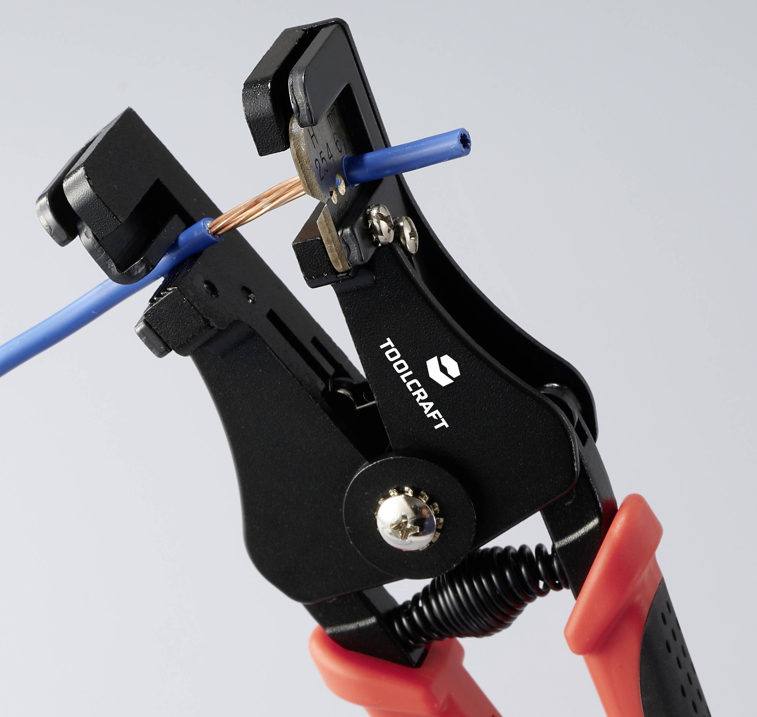 Automatic wire strippers remove the plastic insulation from a blue cable, revealing the inner copper, against a neutral background.